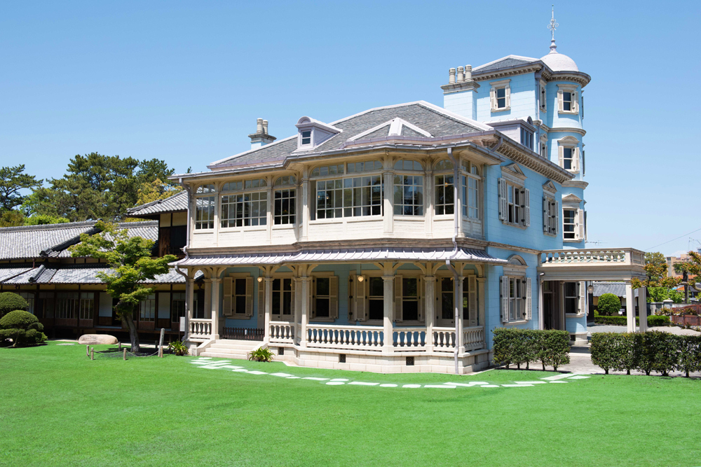 六華苑外観。水色の壁の洋館と、大きな瓦屋根の和館がつながっている
