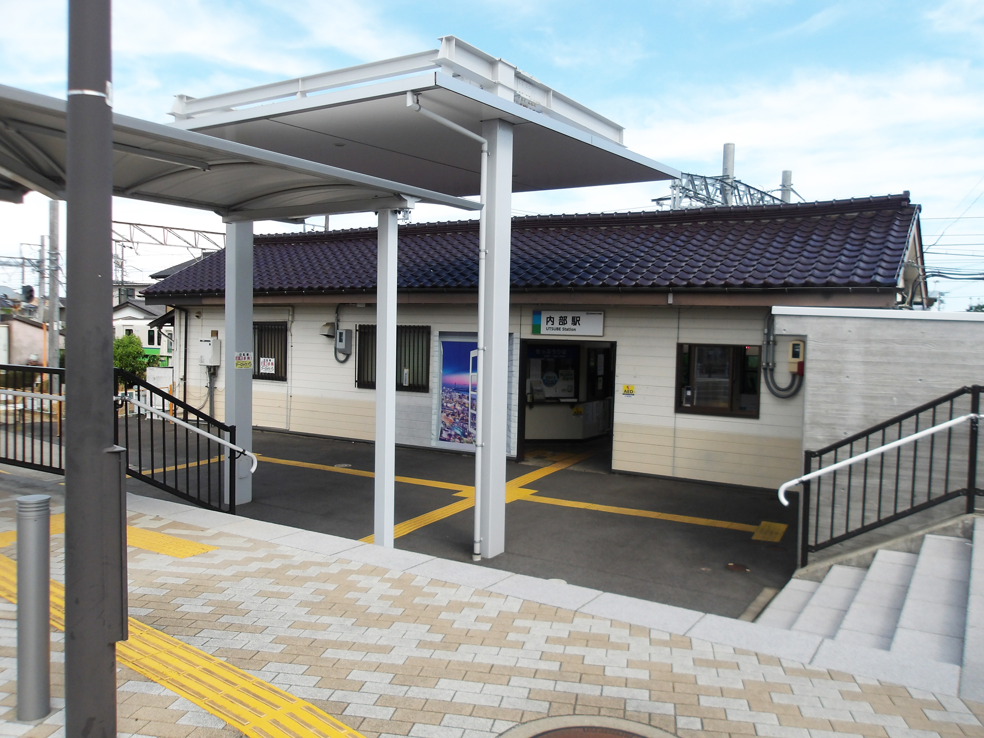 内部駅外観。瓦屋根の駅舎正面と歩行者用の屋根が映っている。