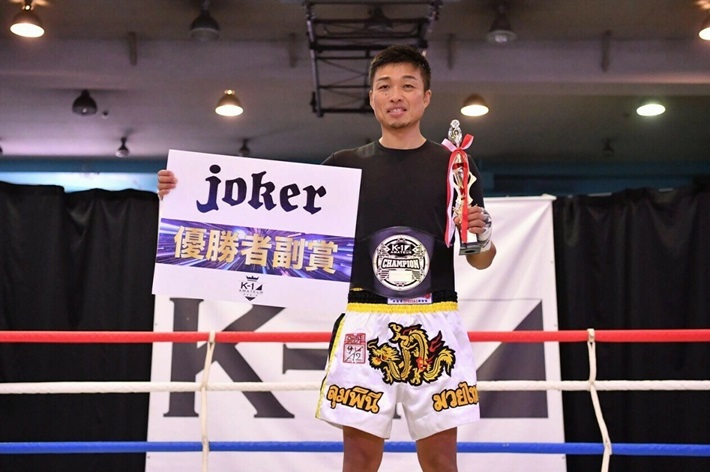 吉川太樹氏がベルトを着けトロフィーを持っている