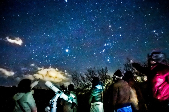 冬の星空と、星空を観察する人々が映った写真